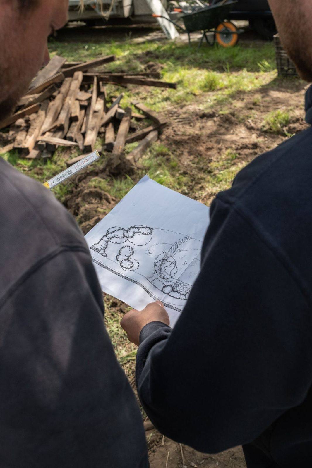 Twee vakmensen van Vijvers Verelst overleggen op de werf met het ontwerpplan